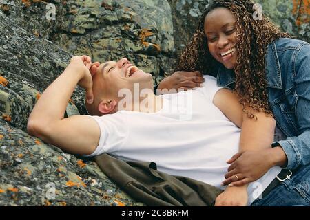 Romantisches Paar am felsigen Ufer lachen und verbinden. Stockfoto