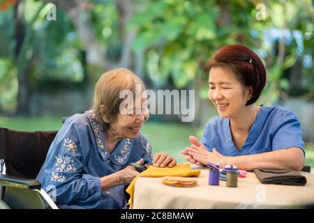 Ältere Frau mit Betreuer in der Nadel Handwerk Ergotherapie für Alzheimer oder Demenz Stockfoto