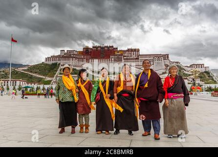 Lhasa, Tibet / China - 29. Jul 2017: Pilger posieren vor dem Potala Palast, Lhasa. Fünf der Pilger tragen orangefarbene Tücher. Tibetischer buddhismus, Squa Stockfoto
