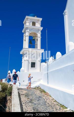 Santorini, Griechenland - 26. April 2019: Menschen auf der Straße, blaue Kuppel Kapelle mit Glockenturm, griechisch orthodoxe Kirche Stockfoto