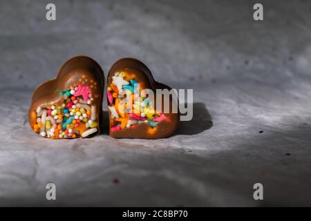 Herzförmige Pralinen mit bunten Streuseln. Stockfoto