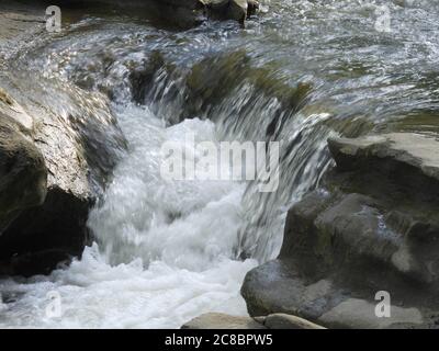 Schöne Nahaufnahme von Wellen, die in einem kleinen Wasserfall zusammenbrechen Stockfoto