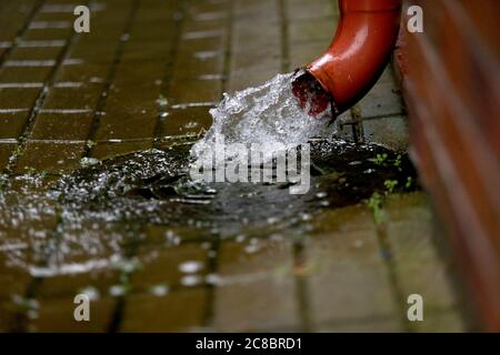 Regenwasser fließt aus der grünen Abflussrinne auf dem Bürgersteig, selektiver Fokus, Nida, Litauen Stockfoto