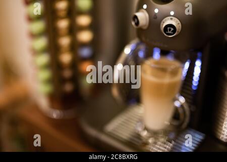 Latte Kaffee mit professioneller Maschine und verschwommene Kapseln Hintergrund Stockfoto