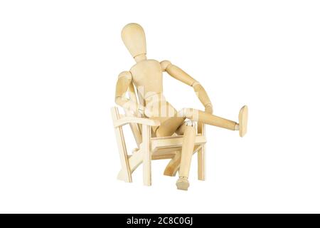 Eine Holzpuppe sitzt auf einem hölzernen Miniaturstuhl auf weißem Hintergrund Stockfoto