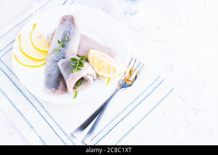 Niederländischer Hering. Traditionelle holländische Küche, mariniertes Fischfilet mit Zwiebeln und Zitrone. Lebensmittel reich an Nährstoffen und Vitaminen. Foto in hellen Farben, freier Platz für Text. Stockfoto