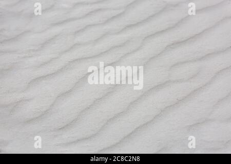 Wellige Textur aus weißem Sand, der im Wind weht. Hintergrund von weißem Sand Natur Textur Stockfoto