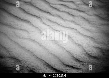 Wellige Textur aus weißem Sand, der im Wind weht. Hintergrund von weißem Sand Natur Textur Stockfoto