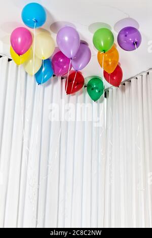 Mehrfarbige Helium-Ballons an der Decke Stockfoto