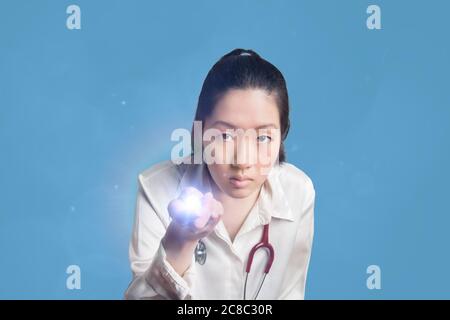 Junge asiatische weibliche Arzt hält eine Taschenlampe Stockfoto