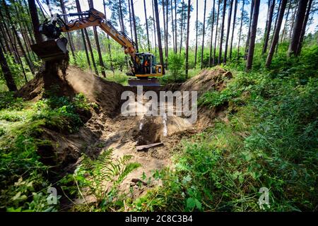 23. Juli 2020, Brandenburg, Grünheide/OT Störitz: Mathieu Barnis von der Firma ARIKON hat mit seinem Bagger den Eingang zu einem ehemaligen russischen Bunker an einem Waldweg freigelegt. Der Bunkerbau ist eine Kompensationsmaßnahme für Eingriffe in die Natur südlich des Tesla-Geländes. Fledermäuse sollen ab der kommenden kalten Jahreszeit im unterirdischen Betongebäude überwintern. Foto: Soeren Sache/dpa-Zentralbild/ZB Stockfoto