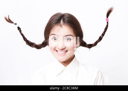 Asiatische Mädchen ziehen lustige Gesicht mit Zöpfen gehen in der Luft Stockfoto