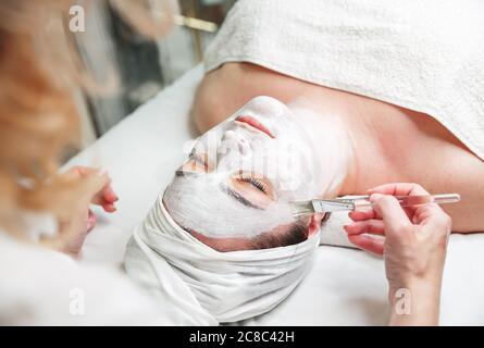 Frau bekommen Gesichtsmaske von Kosmetikerin im Spa Salon. Konzept der Hautbehandlung Stockfoto