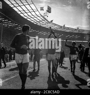 Bobby Moore hebt die Jules Rimet Trophäe während einer Ehrenrunde im Wembley Stadium hoch, während das englische Fußballteam die FIFA-Weltmeisterschaft 1966, Geoff Hurst, Gordon Banks und Roger Hunt in der Nähe gewinnt Stockfoto
