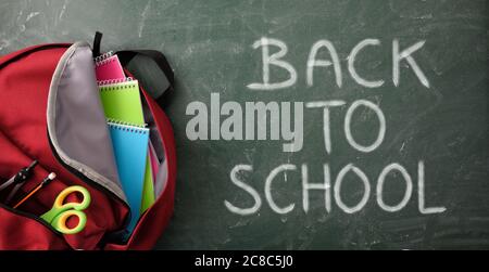 Detail Rucksack voller Schulbedarf auf grüner Tafel mit der Nachricht zurück zur Schule. Draufsicht Stockfoto