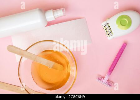 Set für Haarentfernung auf rosa Hintergrund. Enthaarung und Beauty-Konzept - Zuckerpaste oder Wachs Honig für die Haarentfernung mit Holz Wachsspatel Sticks Stockfoto