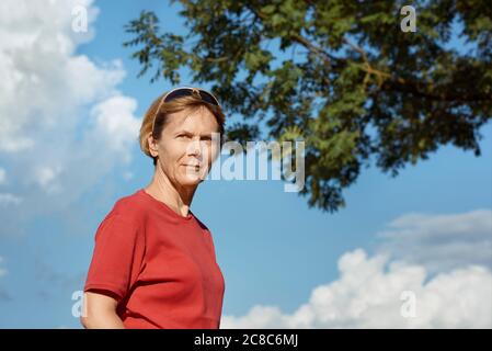 Porträt einer Frau mittleren Alters in einem roten T-Shirt bei schönem Wetter, draußen. Stockfoto