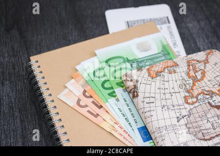 Euro-banknoten auf Notepad und Bordkarte. Das Geld wird auf das Handwerk notepad mit Karte und Airlines Ticket. Stockfoto