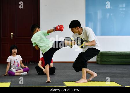 Tianjin, China. Juli 2020. Kinder besuchen während der Sommerferien im pko Sports Complex in Tianjin, Nordchina, am 23. Juli 2020 einen Kampfkunstkurs. Der PKO Sports Complex, der aus einer ehemaligen Fabrik für ausrangierte Zwecke wurde, bietet Einrichtungen wie einen Käfigfußballplatz, eine Basketballhalle, eine Tischtennishalle und ein Kampfkunstklassenzimmer. Er bietet sowohl Sportplätze für die Bewohner in der Nähe als auch mehrere Sporttrainingskurse für die Schüler im Urlaub. Kredit: Sun Fanyue/Xinhua/Alamy Live Nachrichten Stockfoto