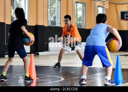 Tianjin, China. Juli 2020. Kinder besuchen während der Sommerferien im pko Sports Complex in Tianjin, Nordchina, am 23. Juli 2020 einen Basketballkurs. Der PKO Sports Complex, der aus einer ehemaligen Fabrik für ausrangierte Zwecke wurde, bietet Einrichtungen wie einen Käfigfußballplatz, eine Basketballhalle, eine Tischtennishalle und ein Kampfkunstklassenzimmer. Er bietet sowohl Sportplätze für die Bewohner in der Nähe als auch mehrere Sporttrainingskurse für die Schüler im Urlaub. Kredit: Li Ran/Xinhua/Alamy Live Nachrichten Stockfoto