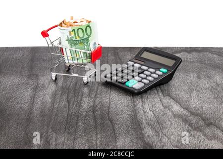 Warenkorb voller Geld und Rechner. Kauf Kostenkalkulation. Shopping consept, euro Geld im Warenkorb. Warenkorb mit Euro auf Grau. Cop Stockfoto