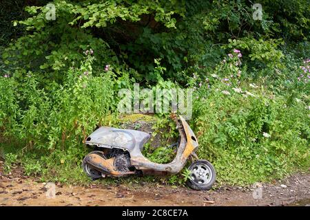 Ein ausgebranntes Moped, das an einer Straßenseite, Cardiff, Südwales, aufgegeben wurde Stockfoto