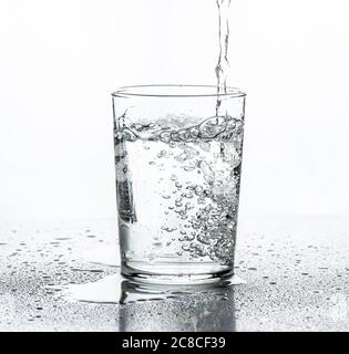 Wasser wird in ein Glas gegossen. Weißer Hintergrund. Stockfoto