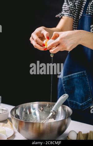 Beschnittene Ansicht der Frau Hände knacken Ei für Kuchen Teig Stockfoto