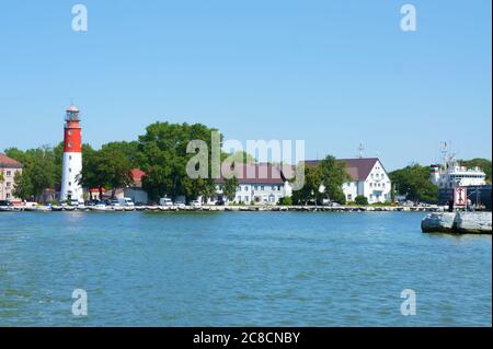 Der Damm am Kanal, der rot-weiße Leuchtturm am Ufer, Baltijsk, Kaliningrad, Russland, 20. Juli 2019 Stockfoto