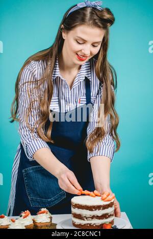 Happy Gebäck Frau in Stripped Bluse Dekoration Kuchen mit Erdbeere Stockfoto