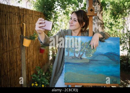 Künstlerin macht Selfie mit ihrer Malerei Stockfoto