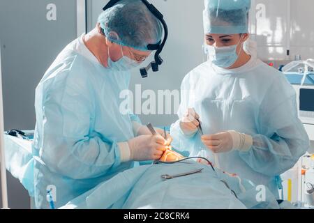 Team von Chirurgen in Uniform führen Operation an einem Patienten in der Klinik für plastische Chirurgie Stockfoto