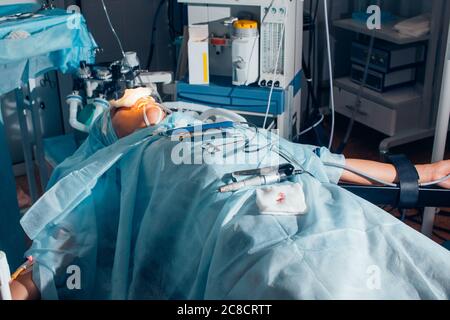 Der Patient, der auf dem Bett liegt, rastet den Arm mit Baumwolle auf dem Operationstisch Stockfoto