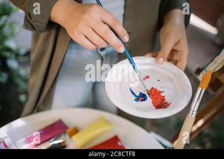 Weibliche Künstler Hände mischen Farben in Teller Stockfoto