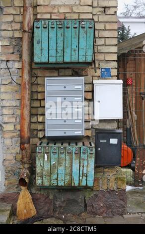 Alte und neue rostige Briefkästen an der Wand eines gelben Backsteinhauses der alten Stadt montiert Stockfoto