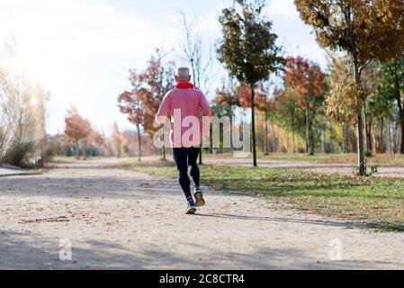 Rückansicht eines älteren Mannes in Sportkleidung Joggen im Park an einem sonnigen Tag Stockfoto