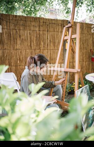 Fokussierter Künstler Vorbereitung Leinwand stehen für die Platzierung Leinwand im Hof Stockfoto