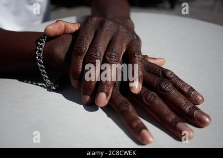 Nahaufnahme, Hände auf dem Tisch, der Mann ist Afrikaner. Schwarze Haut. Hochwertige Fotos Stockfoto