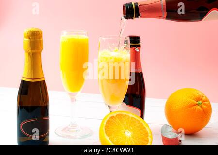 Üppige Mixgetränke, sommerliche alkoholische Getränke und erfrischendes Brunch Mimosa Cocktail-Konzept mit Orangenfrüchten und Champagner aus einer Flasche BU Stockfoto