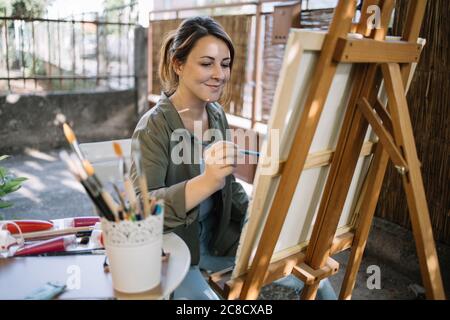 Lächelnder Maler, der mit Aquarellfarbe und Pinsel ein Bild zeichnet Stockfoto