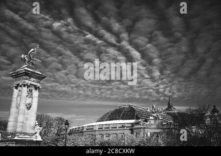 Paris im Schnee. Blick auf den Grand Palais von der Alexandre III Brücke. Wunderschöne Wolkenlandschaft. Schwarz weiß historisches Foto Stockfoto