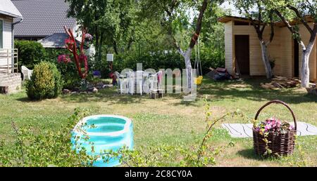 Hinterhof eines armen Dorfhauses mit einem Kinderplastiktüte im Vordergrund. Sonnige Sommertag Panorama-Landschaft Stockfoto