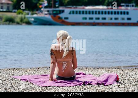 Speyer, Deutschland. Juli 2020. Eine Frau liegt auf einer Decke am Rheinufer. Im Hintergrund ist ein Flusskreuzfahrtschiff zu sehen. Quelle: Uwe Anspach/dpa/Alamy Live News Stockfoto