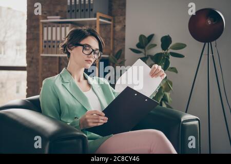 Konzentriert gesinnten Führer Vermarkter Chef Finanzier Mädchen sitzen Ledersessel Clip-Board lesen Analyse Startup Entwicklung Fortschritt Präsentation Verschleiß Stockfoto