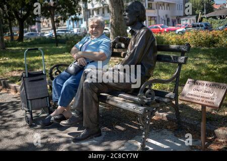 Belgrad, Serbien, 9. Juli 2020: Eine Frau, die auf einer Bank neben einer Bronzestatue sitzt Stockfoto