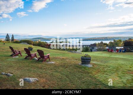 Leere Stühle in einer Reihe mit Blick auf einen herrlichen Bergsee an einem klaren Herbstmorgen. Laconia, NH, USA. Stockfoto