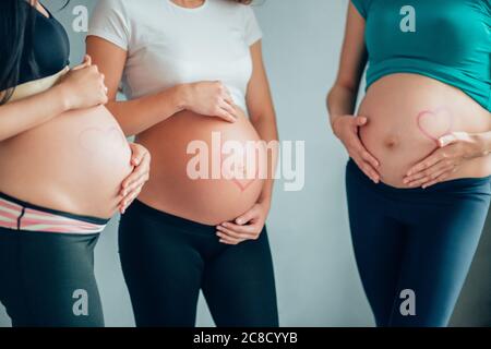 Mutterschaftskonzept. Porträt von drei glücklichen schwangeren Frauen. Stockfoto