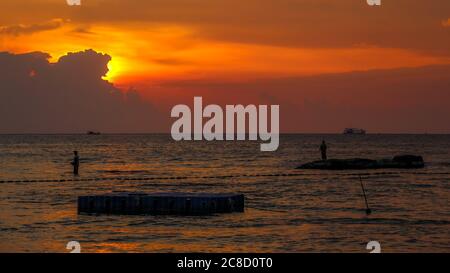 Eine Silhouette von Fischern, die bei Sonnenuntergang am Strand von Ba Keo auf den Felsen stehen, Phu Quoc Island, Vietnam Stockfoto