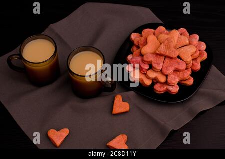 Kekse mit roten herzförmigen und zwei Tassen Kaffee mit Milch, Valentinstag Stockfoto