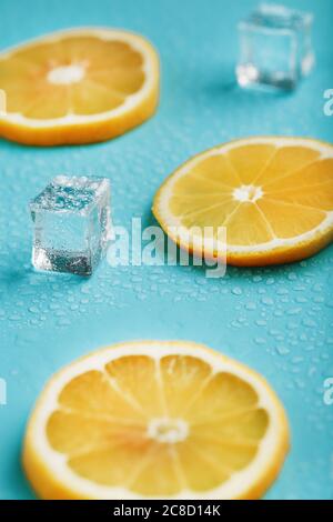 Frische Zitrone mit Eis und Tropfen auf blauem Hintergrund. Stockfoto